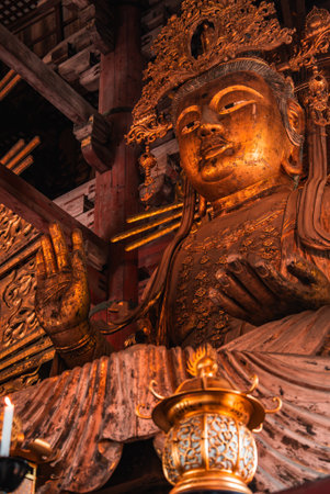 Gilded Buddhist statue in Nara temple interior with blessing gestureの写真素材