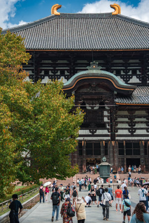 Crowds approach Todai ji Daibutsuden in Nara under autumn lightの写真素材