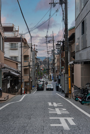 Kyoto street with wooden facades, power lines, and evening walkersの写真素材