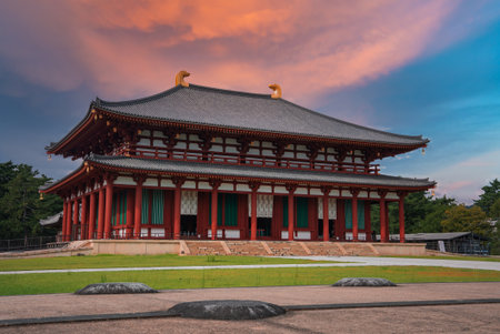 Nara temple hall with vermilion wood and golden roof ornaments at sunsetの写真素材