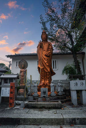 Kannon statue with attendants in Kyoto temple courtyard at sunsetの写真素材