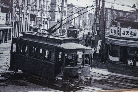 Historic Hiroshima streetcars turn through a busy city intersectionの写真素材
