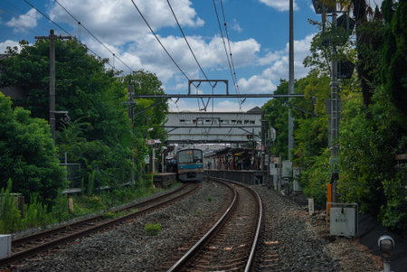 Curving suburban rail line with commuter train approaching Kyoto stationの写真素材