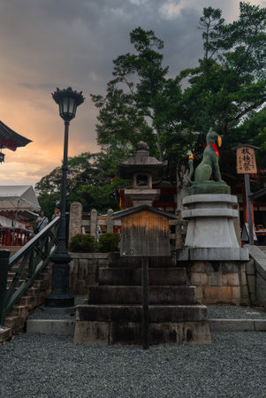 Stone fox statue and lantern at Fushimi Inari Taisha at dusk, Kyotoの写真素材