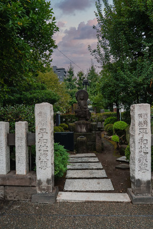 Stone pathway to a seated Buddha in a small Tokyo temple gardenの写真素材