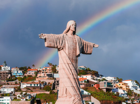 Cristo Rei at Garajau with rainbow above coastal homes, Madeiraの写真素材