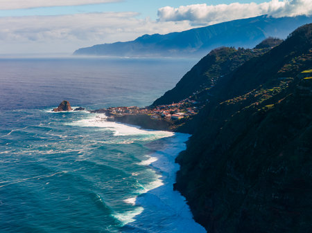 Aerial view of Madeira north coast cliffs, village, and Atlantic surfの写真素材