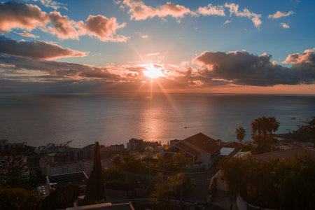 Sunset over Funchal Madeira bay with terraced rooftops and boats