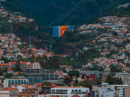 Funchal hillside city, bridge with Madeiran flag, evening light
