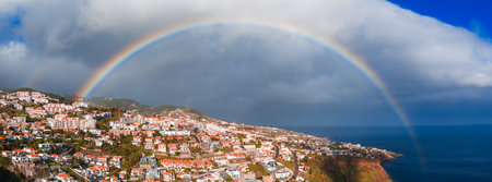 Rainbow over Funchal, Madeira, terracotta roofs and Atlantic coastの写真素材