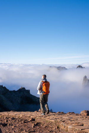 Hiker on rocky trail above clouds at Pico do Arieiro, Madeiraの写真素材