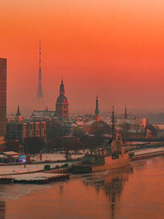Riga Old Town at winter sunset with Riga TV Tower and river warship