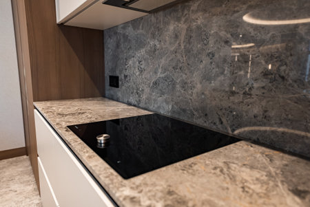 Modern luxury kitchen with black induction cooktop and marble finishesの写真素材