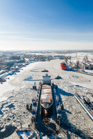 Aerial winter view of Riga Shipyard, Daugava River, ice and cranes