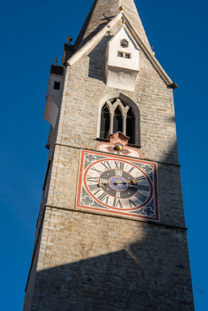 Stone bell tower of Cathedral of Brixen in Italy with ornate clock