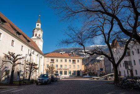 Sunlit town square in Brixen with church tower and Alpine backdrop