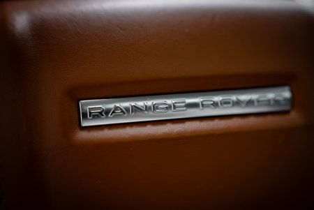 Range Rover badge inset in brown leather, indoor shallow focus view