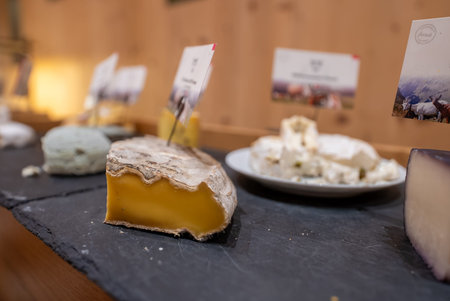Artisanal cheese tasting display on slate with aged wedge focus