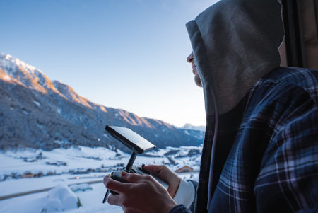 Drone controller by window over Dolomites valley at sunrise or sunsetの写真素材