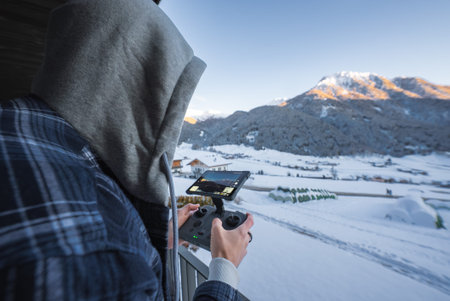 Person operates drone controller on balcony in Dolomites resort winter