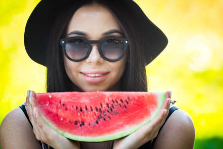 Glamorous girl in a hat and glasses with a watermelon in hand.の写真素材