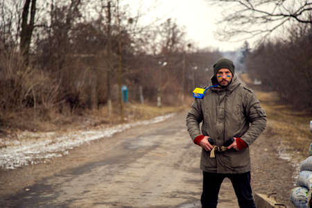 A Ukrainian man with a weapon at a checkpoint. A Ukrainian patriot guards the entrance to his village.の写真素材