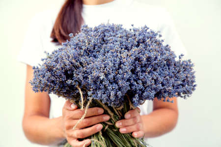 Portrait of a beautiful young woman with a bouquet of lavender in her hands. Happy young girl with a bouquet of lavender flowers. The concept of happiness, beauty and nature.の写真素材