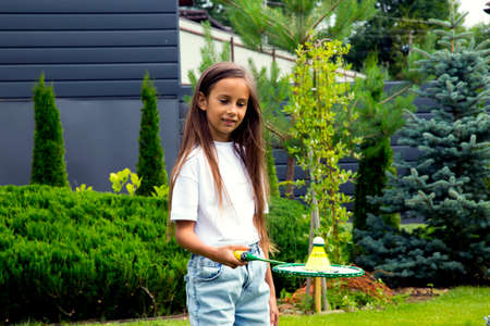 Happy little girl playing badminton in the park. Portrait of a girl with badminton in her hands in...