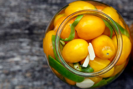 Fresh organic yellow tomatoes in a jar. Organic non-GMO yellow tomatoes on a canning table. The...