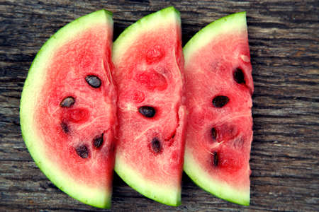 Juicy fresh red watermelon on the table. Watermelon sliced into pieces on a wooden texture...