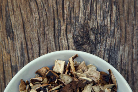 Dried natural porcini mushrooms in a plate. White mushrooms in a bowl on a wooden background. The...