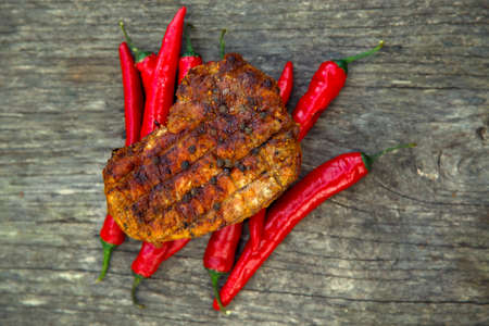 Meat steak cooked on the barbecue. Grilled fresh meat steak with spices and red pepper. Ready steak on the table with tomatoes and peppers. The concept of food, restaurants, traditionの写真素材