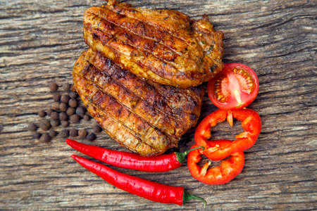 Meat steak cooked on the barbecue. Grilled fresh meat steak with spices and red pepper. Ready steak on the table with tomatoes and peppers. The concept of food, restaurants, traditionの写真素材