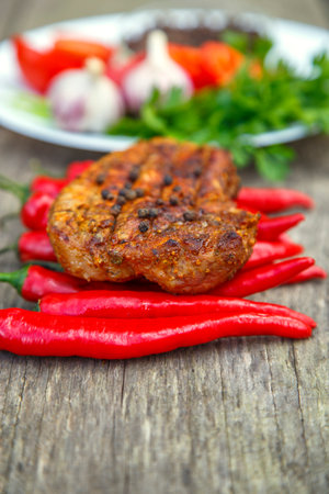 Meat steak cooked on the barbecue. Grilled fresh meat steak with spices and red pepper. Ready steak on the table with tomatoes and peppers. The concept of food, restaurants, traditionの写真素材