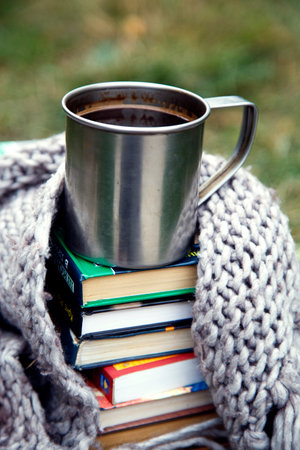 Cup of coffee and books on a blanket in the park.A cup of coffee on a background of books and a blanket.の写真素材