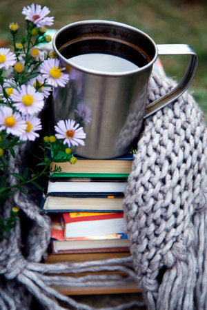 Cup of coffee with books and knitted scarf on wooden background.A cup of coffee on a background of books and a blanket.の写真素材