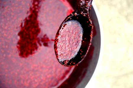 Cherry jam in a bowl with spoon on a light background. Raspberry jam in canning jars. Berry jam made...