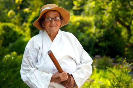 An old lady in a kimono in a park. Portrait of an old lady training in the garden. The concept of old age, nature.の写真素材