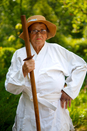 An old lady in a kimono in a park. Portrait of an old lady training in the garden. The concept of old age, sports, nature.の写真素材