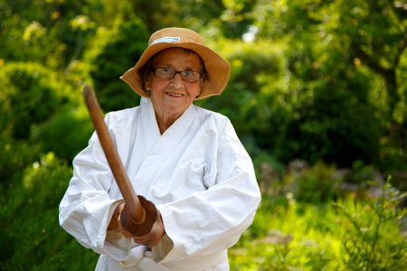 An old lady training with a sword in the garden. The concept of old age, sports, nature.の写真素材