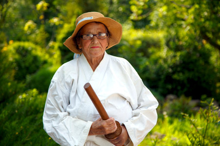 An old lady in a kimono in a park. Portrait of an old lady training in the garden. The concept of old age, sports, nature.の写真素材