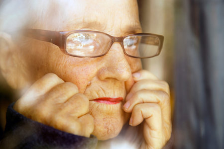 Portrait of an old woman with glasses reflected in a window. The face of an elderly woman with...