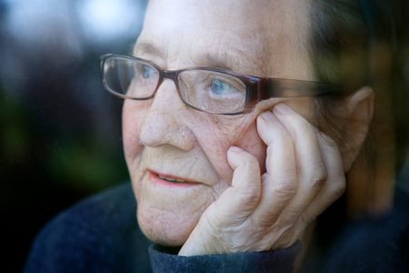 Portrait of an old woman with glasses reflected in a window. The face of an elderly woman with...