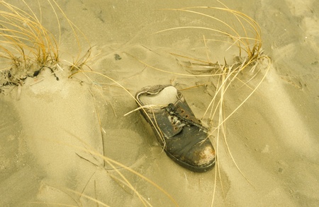 Old shoe in the sand as jetsam at the beach of the Danish isle RÃ¸mÃ¸.の写真素材
