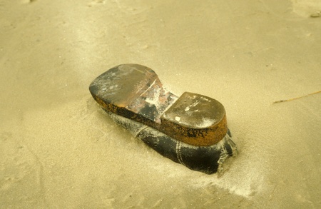 Old shoe in the sand as jetsam at the beach of the Danish isle RÃ¸mÃ¸.