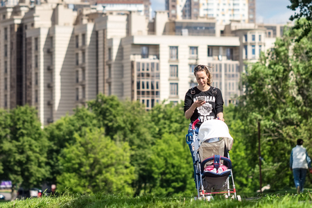 MOSCOW, RUSSIA - YULI 20, 2017: Unidentified young mother with a baby in a stroller.のeditorial素材