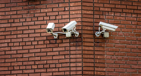 Three surveillance cameras installed on the brick wall of the building.