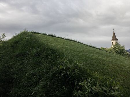 Hill with grass on a cloudy day in an urban setting