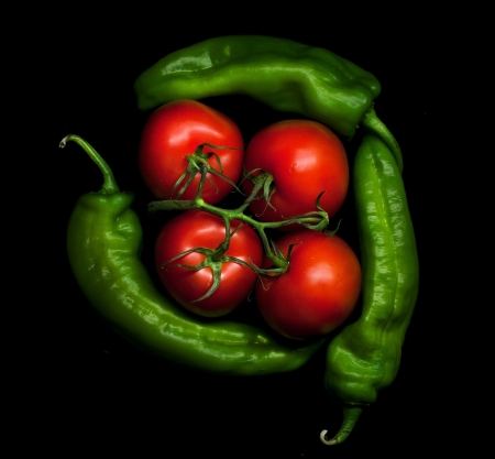 Tomatoes and green peppers isolated on black backgroundの写真素材