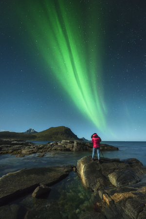 Woman taken pictures under the Northern Lights, Lofoten, Norwayの写真素材